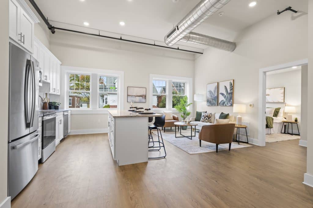 Loft at Lofts on Broad, Souderton, with open kitchen island, stainless appliances, exposed ductwork and furnished living area.