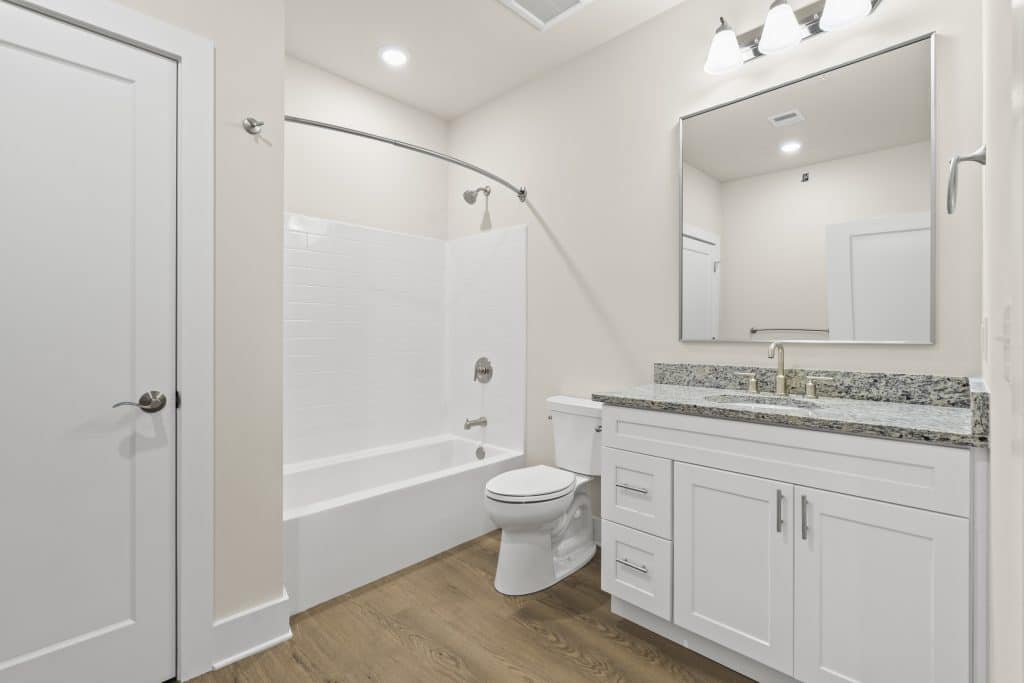 Lofts on Broad bathroom in Souderton with white tub/shower and curved rod, white vanity with granite countertop and mirror.