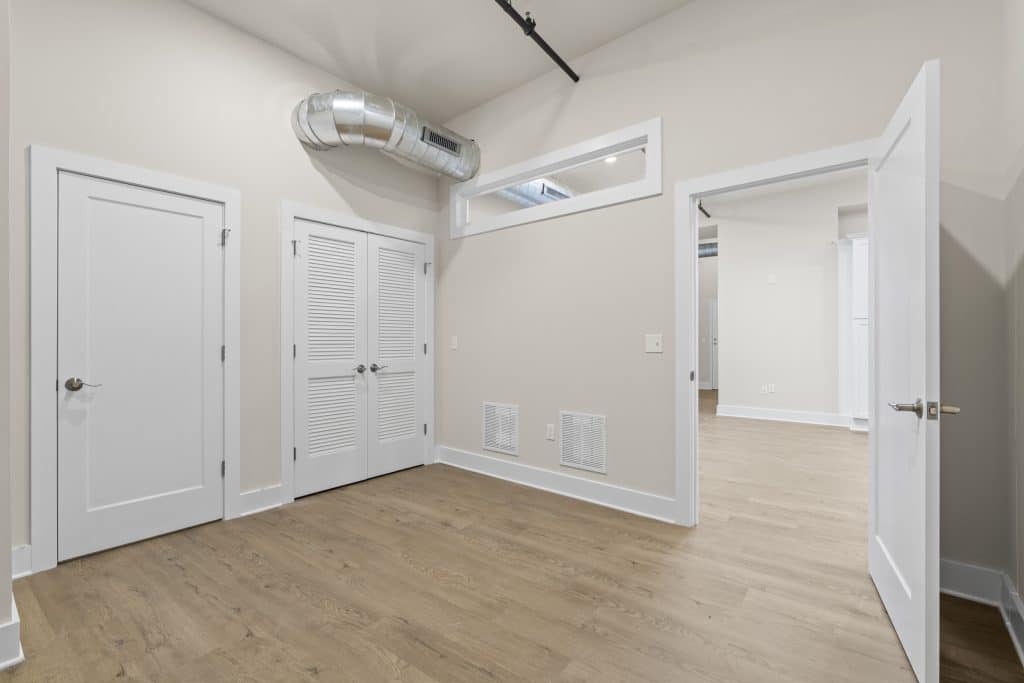 Empty loft at Lofts on Broad, Souderton PA with light wood floors, white doors and trim, louvered closet doors and exposed duct.