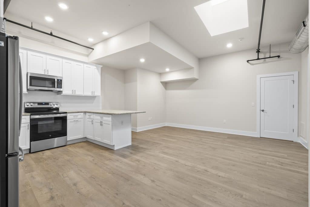 Loft at Lofts on Broad, Souderton PA with white kitchen cabinets, stainless appliances, skylight, and wood floors.