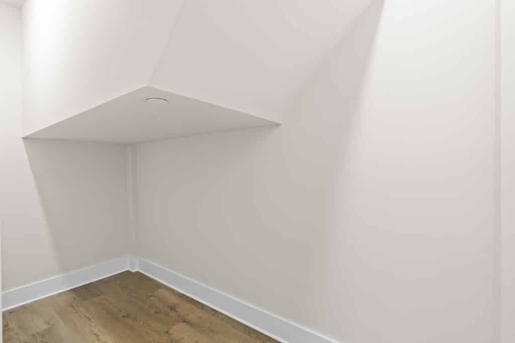 Small white alcove under a sloped ceiling with recessed light, wood floor and white baseboards at Lofts on Broad.