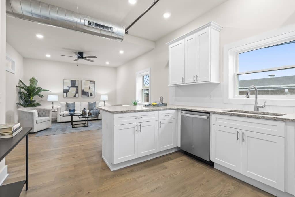 Loft kitchen at Lofts on Broad with white cabinets, granite counters, stainless dishwasher, exposed ductwork.