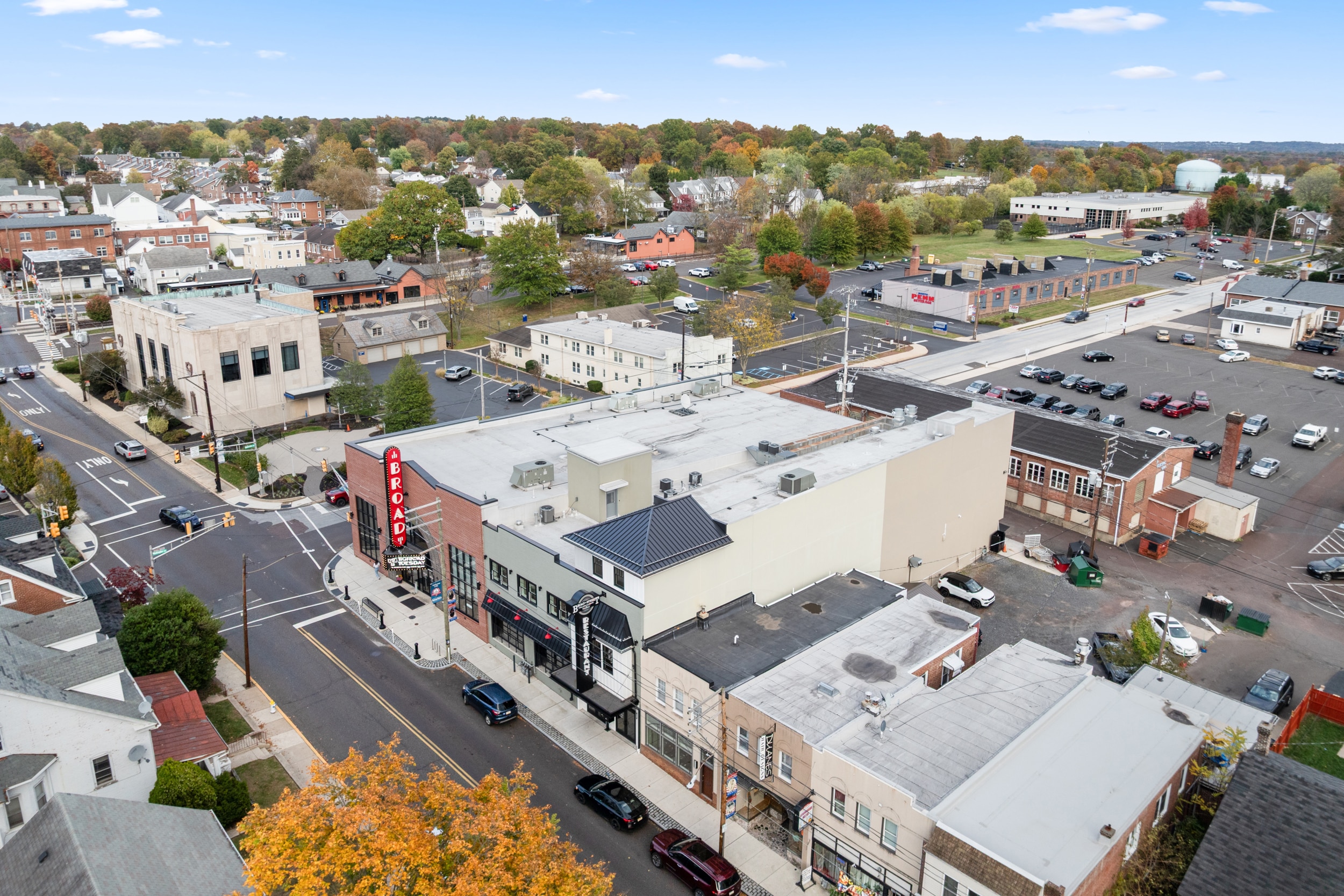 Aerial view of Lofts on Broad in Souderton, PA with a vertical BROAD marquee, adjacent storefronts, streets and autumn trees.